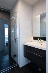La salle de bains est pourvue d'un lavabo et d'une douche en verre. dans l'établissement CHELSEABAY Modern Apartments, à Auckland