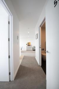un couloir avec des murs blancs ainsi que des sols et des portes blancs dans l'établissement CHELSEABAY Modern Apartments, à Auckland