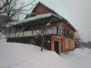 um edifício com neve no chão à sua frente em Apartman Štimac em Crni Lug