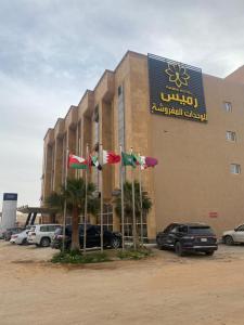 un hotel con banderas delante de un estacionamiento en رميس البخاري en Buraidah