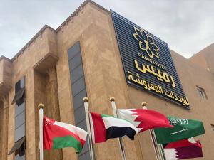 um edifício com três bandeiras à sua frente em رميس البخاري em Buraydah