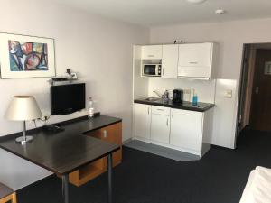 een kamer met een keuken met een bureau en een magnetron bij Apartment 31 in Sindelfingen