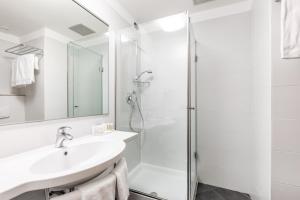 La salle de bains blanche est pourvue d'un lavabo et d'une douche. dans l'établissement Anusca Palace Hotel, à Castel San Pietro Terme