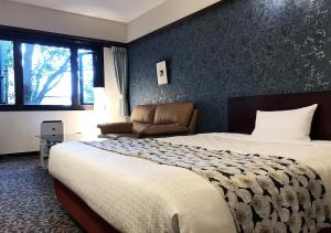 a hotel room with a bed and a couch at Hotel Okus in Kumamoto