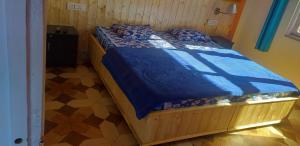 Schlafzimmer mit einem Holzbett mit blauer Decke in der Unterkunft Shanti Jungle cottage in Mashobra