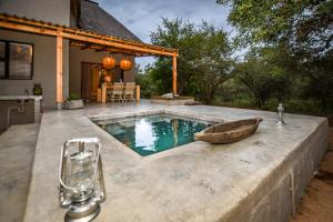 una piscina con un barco de madera en un patio en Khiza Bush Retreat, en Hoedspruit