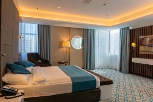 um quarto de hotel com uma cama grande e uma secretária em Royal Crown Hotel em Mascate