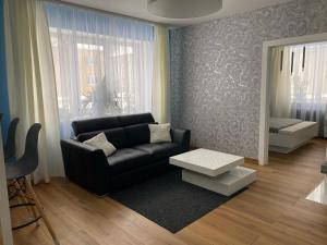 a living room with a black couch and a table at Rezekne Lux Apartments in Rēzekne