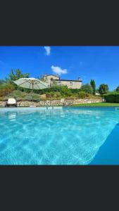 una gran piscina de agua azul con sombrilla en Chianti Suite, en Castellina in Chianti