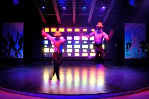 two men dancing on a stage with their arms up at Belcekiz Beach Club - All Inclusive in Oludeniz