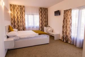 a bedroom with a bed and a television and curtains at Complex Carol in Buzau