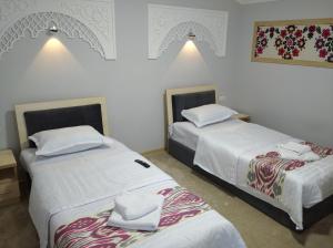 Dos camas en una habitación de hotel con sábanas blancas. en Green House ECO HOTEL, en Samarkand 95 fotos más