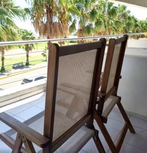 een houten stoel op een balkon met een raam bij Andaluhe Posada in Miramar