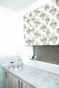 a bathroom with a sink and a flower shower curtain at Apartments on Yavornitsky av. in Dnipro