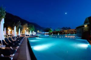 a swimming pool with chairs and umbrellas at night at Belcekiz Beach Club - All Inclusive in Oludeniz