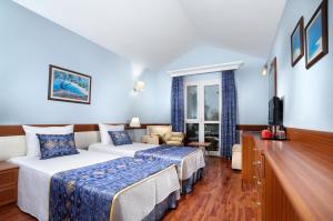 a hotel room with two beds and a flat screen tv at Belcekiz Beach Club - All Inclusive in Oludeniz
