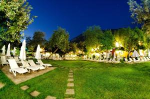 a lawn with chairs and umbrellas at night at Belcekiz Beach Club - All Inclusive in Oludeniz