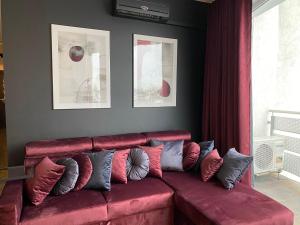 a living room with a red couch with pillows at Family & Business Sauna Apartments Klonowa nad Zalewem, Unikat SPA - 2 Bedroom with Private Sauna, Jacuzzi, Spectacular Terrace, Air Conditioning, Garage - The Highest Standard! in Kielce