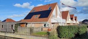 uma casa com um painel solar no telhado em Nieuw Strand em Petten