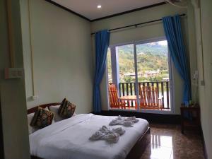 a bedroom with a bed and a large window at Arthith Guesthouse in Nongkhiaw