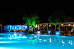 a swimming pool at night with tables and chairs at Belcekiz Beach Club - All Inclusive in Oludeniz