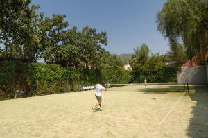 a person is playing tennis on a tennis court at Belcekiz Beach Club - All Inclusive in Oludeniz