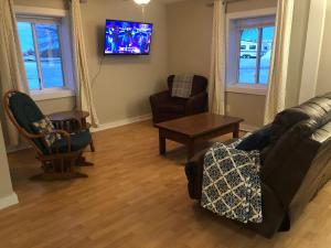 - un salon avec un canapé, des chaises et une télévision dans l'établissement Burrel Avenue Apartments, à Cooperstown