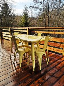 una mesa amarilla y sillas en una terraza de madera en Les Cottages Barisiens, en Bar-le-Duc