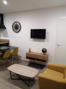 sala de estar con TV, mesa y sillas en Les Cottages Barisiens, en Bar-le-Duc