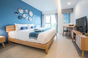een slaapkamer met een bed en een blauwe muur bij DeeProm Pattaya Hotel in Pattaya