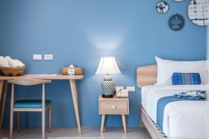 een slaapkamer met blauwe muren en een bed en een bureau bij DeeProm Pattaya Hotel in Pattaya