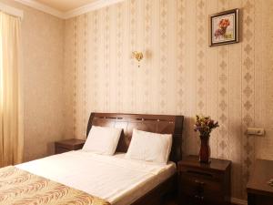1 dormitorio con 1 cama con sábanas blancas y un jarrón de flores en Your Getaway Home, en Ereván