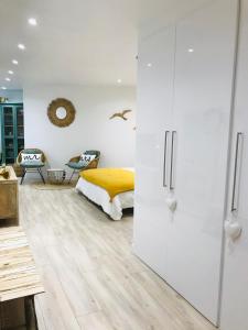 a bedroom with white walls and a bed with yellow sheets at Cocon douillet face à la mer de Cagnes sur mer in Cagnes-sur-Mer