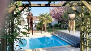 a swimming pool in a backyard with a pergola at Chambre d'Hôtes Armoise in Lagord +6 photos