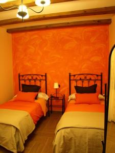 2 camas en una habitación con paredes de color naranja en Apartamentos Rurales El Palomar, en Villar del Humo