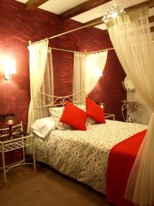 1 dormitorio con cama con dosel y almohadas rojas en Apartamentos Rurales El Palomar, en Villar del Humo
