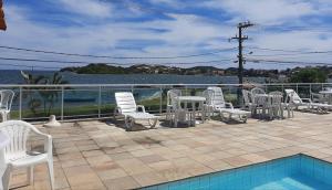 a patio with white chairs and a swimming pool at Vista Panorâmica em São Pedro da Aldeia in Rio de Janeiro