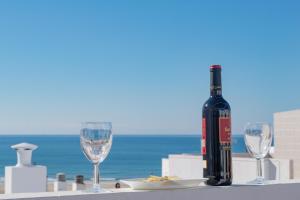 een fles wijn zittend op een tafel met twee wijnglazen bij Conil town house with roof terrace and great views, Baluarte in Conil de la Frontera