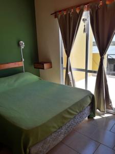 a bedroom with a green bed and a window at Cabañas bajos medanales in Victorica