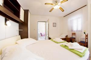 a bedroom with a white bed and a ceiling fan at Beachfront house Pope B&B in Selca