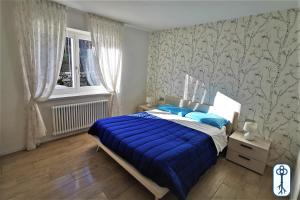 1 dormitorio con cama con sábanas azules y ventana en Casa Vacanze Antico Eremo, tra natura e tradizione, en Campodenno