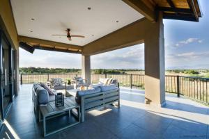a patio with couches and a table on a deck at Zebula Golf Estate & Spa Executive Holiday Homes in Mabula