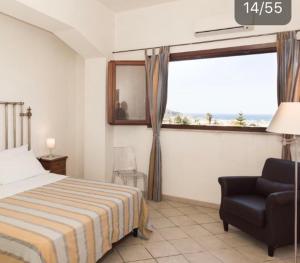 a bedroom with a bed and a chair and a window at Casale Belvedere vista mare in Valderice