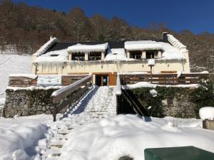 una casa cubierta de nieve delante en Ô Chiroulet - Le Refuge de l'Isard, en Bagnères-de-Bigorre