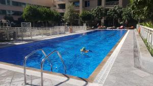 a person swimming in a large blue swimming pool at Durrani Homes - Designer 2BR Apt with stunning Burj khalifa and Fountain View in Dubai