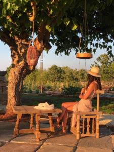 a woman sitting on a bench under a tree at I Trulli di Alice in Ceglie Messapica