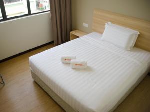 a bedroom with a white bed with two boxes on it at 1 Orange Hotel Sungai Buloh in Sungai Buluh