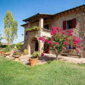 a stone house with flowers and plants in front of it at Podere La Vecchia Fornace in Cortona