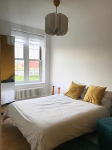 sypialnia z dużym białym łóżkiem z żółtymi poduszkami w obiekcie Riverside Cutty Sark 2BD Retreat w Londynie