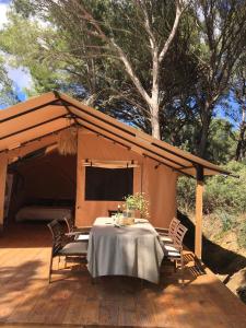 a tent with a table and chairs on a deck at Saint Paul le Marseillais Tentes Equippees Hébergements Insolites Lodges in Mèze +18 photos